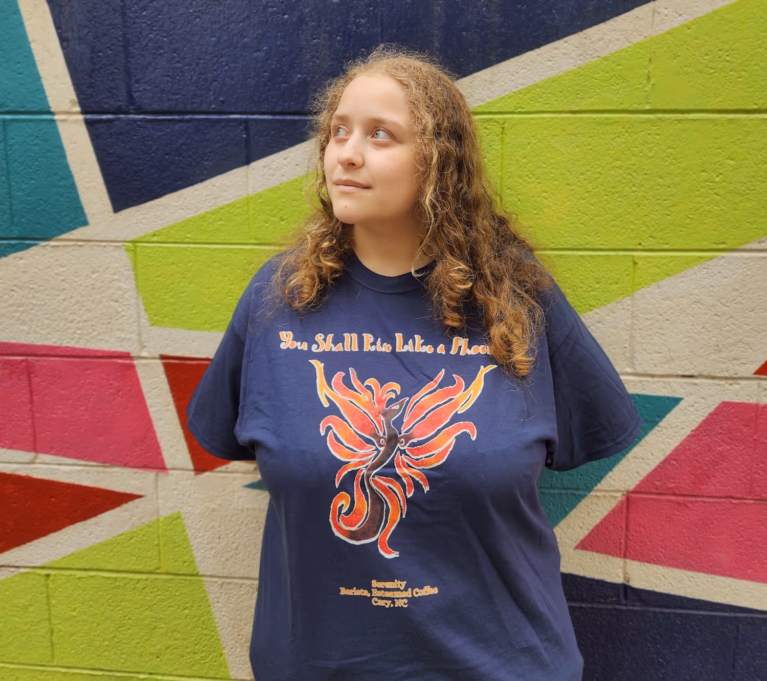 Barista Serenity posing wearing her "We shall rise like a phoenix" shirt