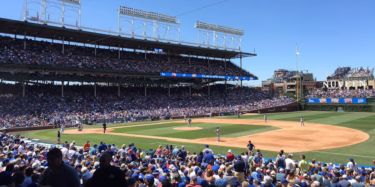 A sunny baseball game at a stadium packed with fans wearing blue and white.