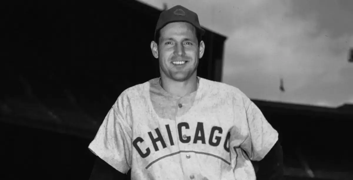 Smiling baseball player wearing a Chicago uniform and cap in a stadium.