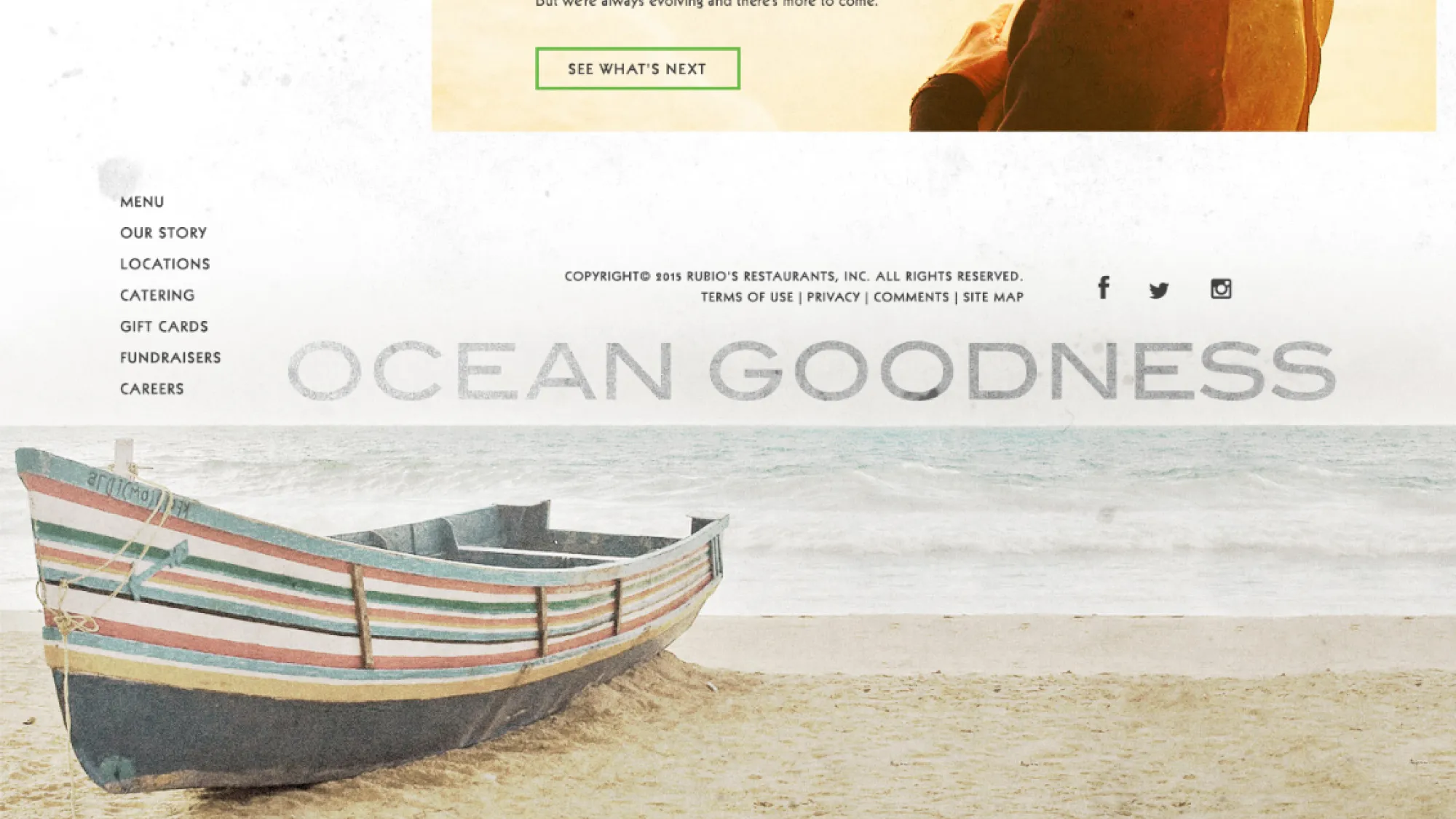 Striped wooden boat resting on sandy beach with ocean waves in the background.
