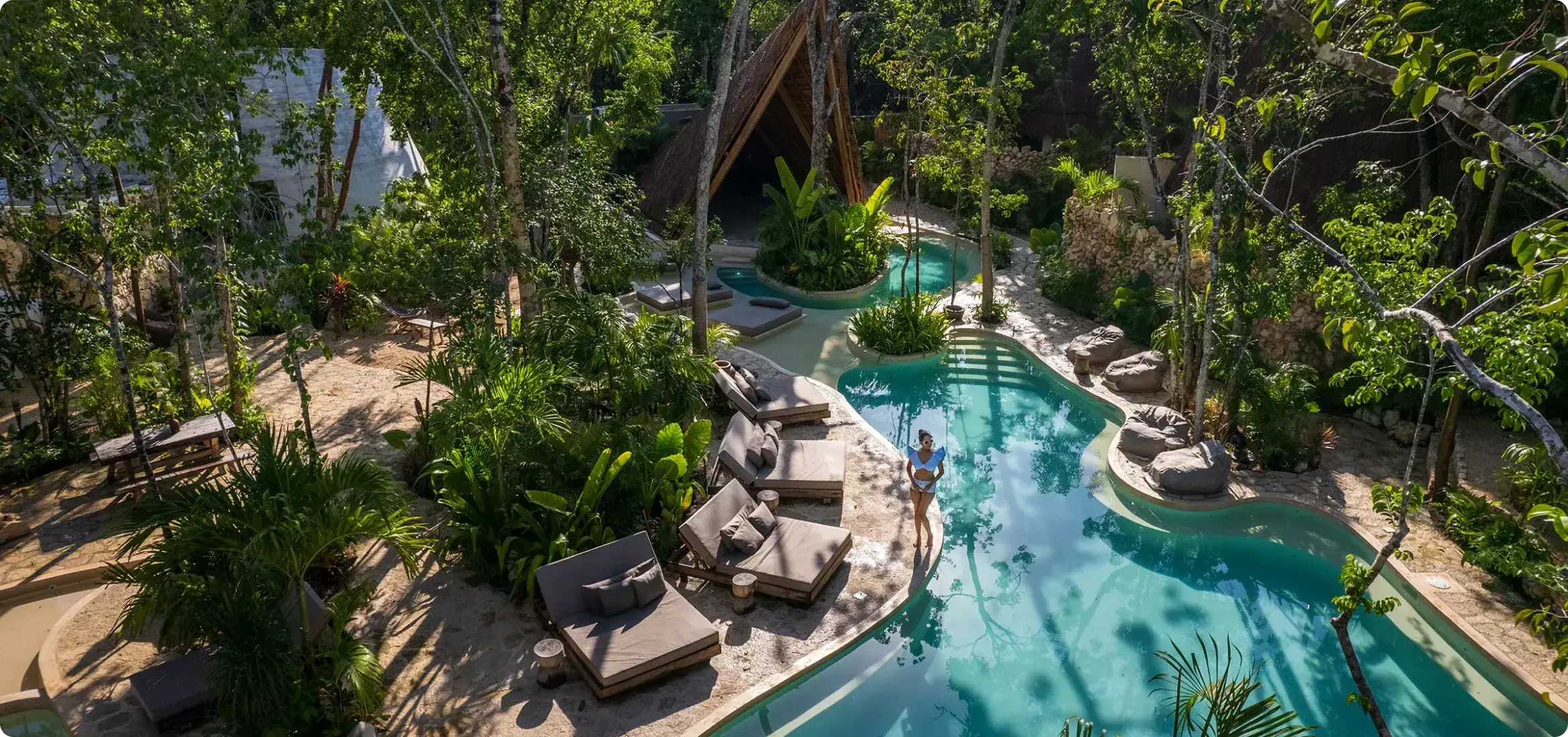mujer-en-alberca-vista-aerea-vegatcion-tropical-camastros