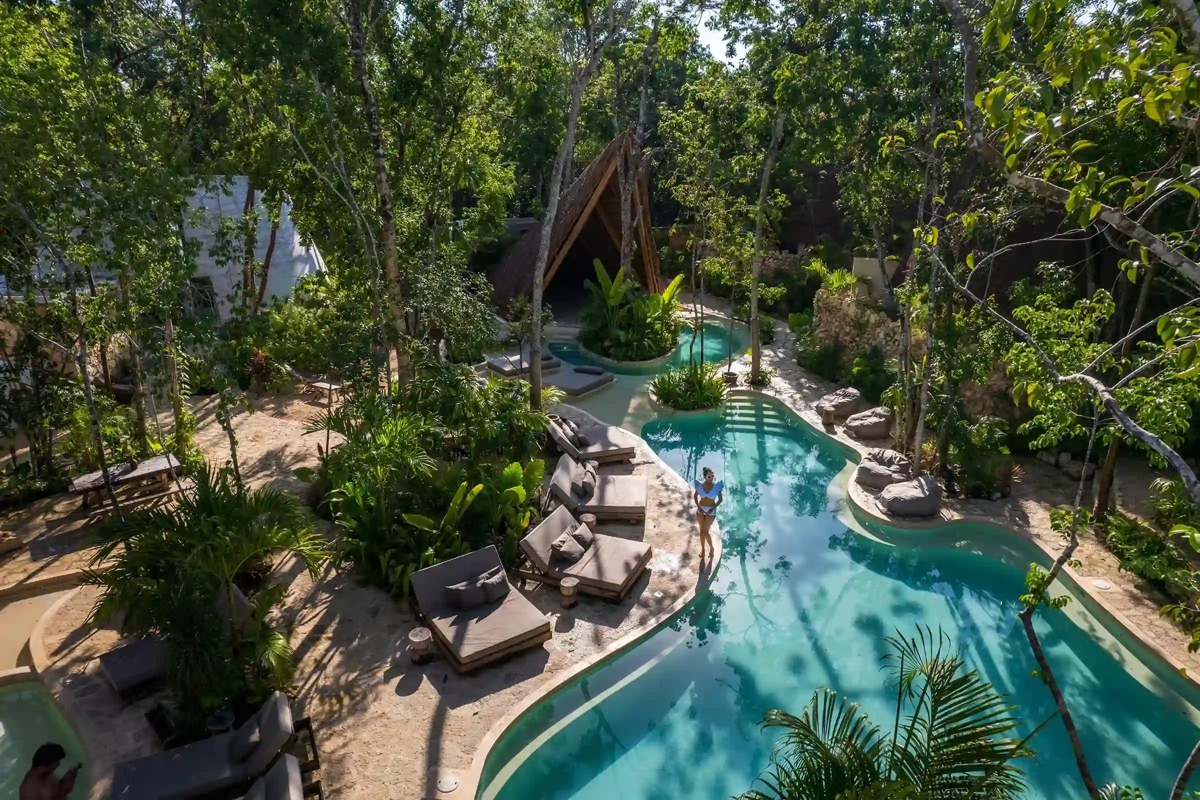 vista-aerea-mujer-alberca-vegetacion-tropical-camastros