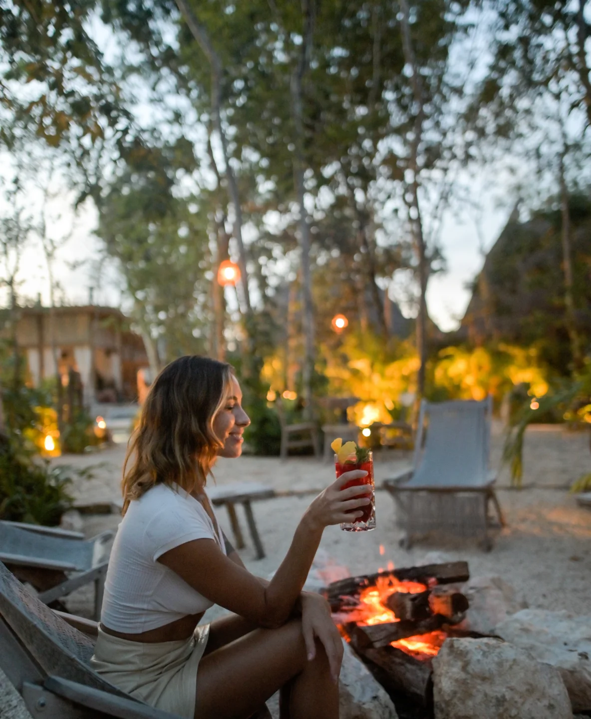 mujer-con-bebida-en-la-mano-disfrutando-fogata-en-la-playa