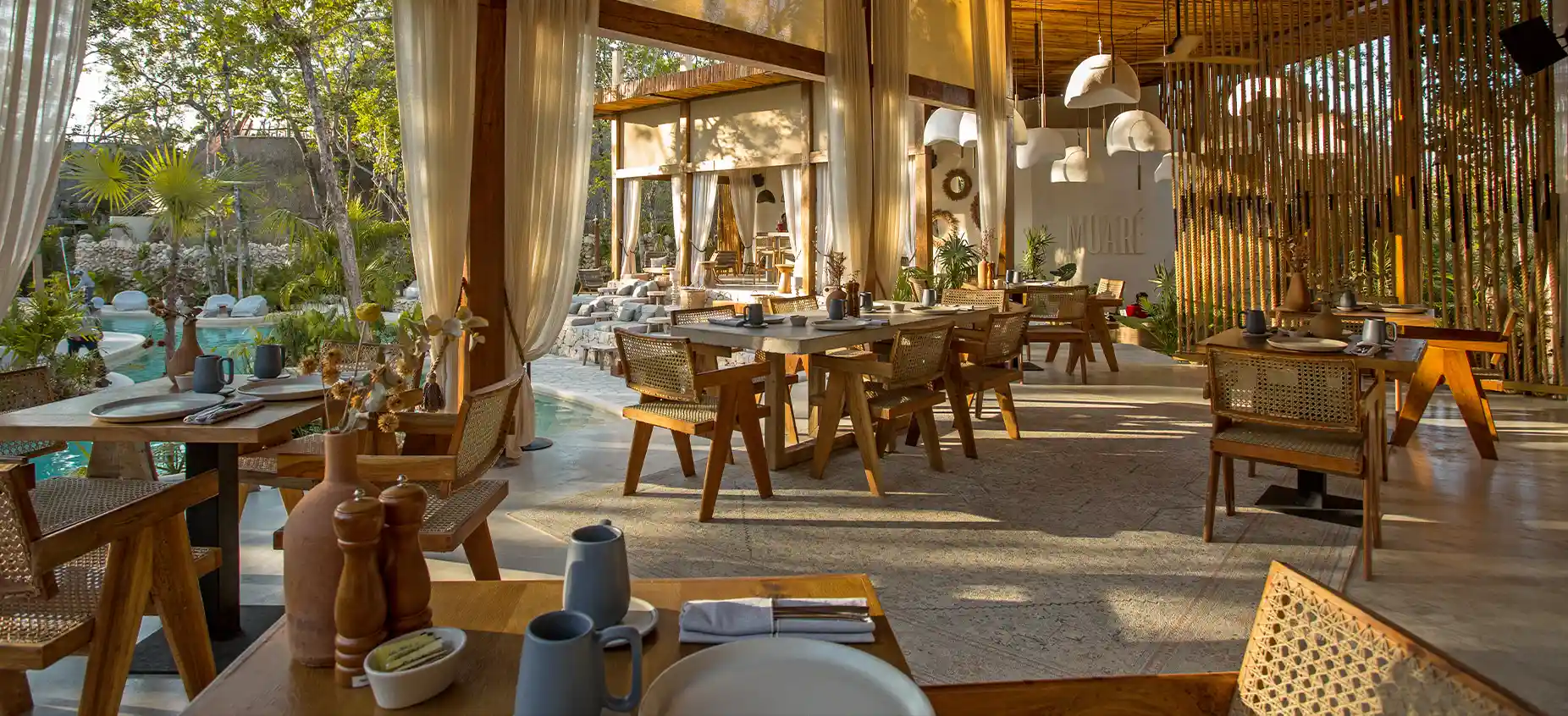 Restaurante elegante con mesas y sillas junto a una piscina.