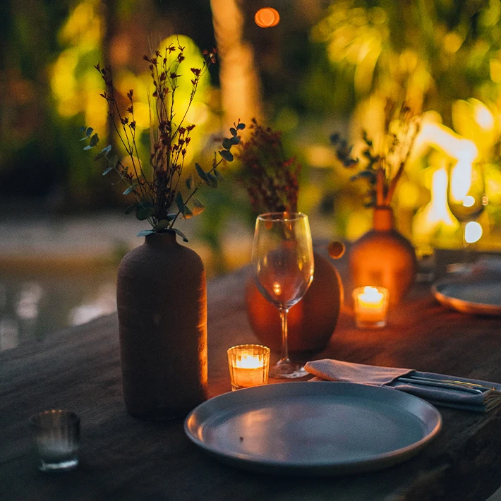Mesa elegantemente decorada con velas, flores y copas de vino.