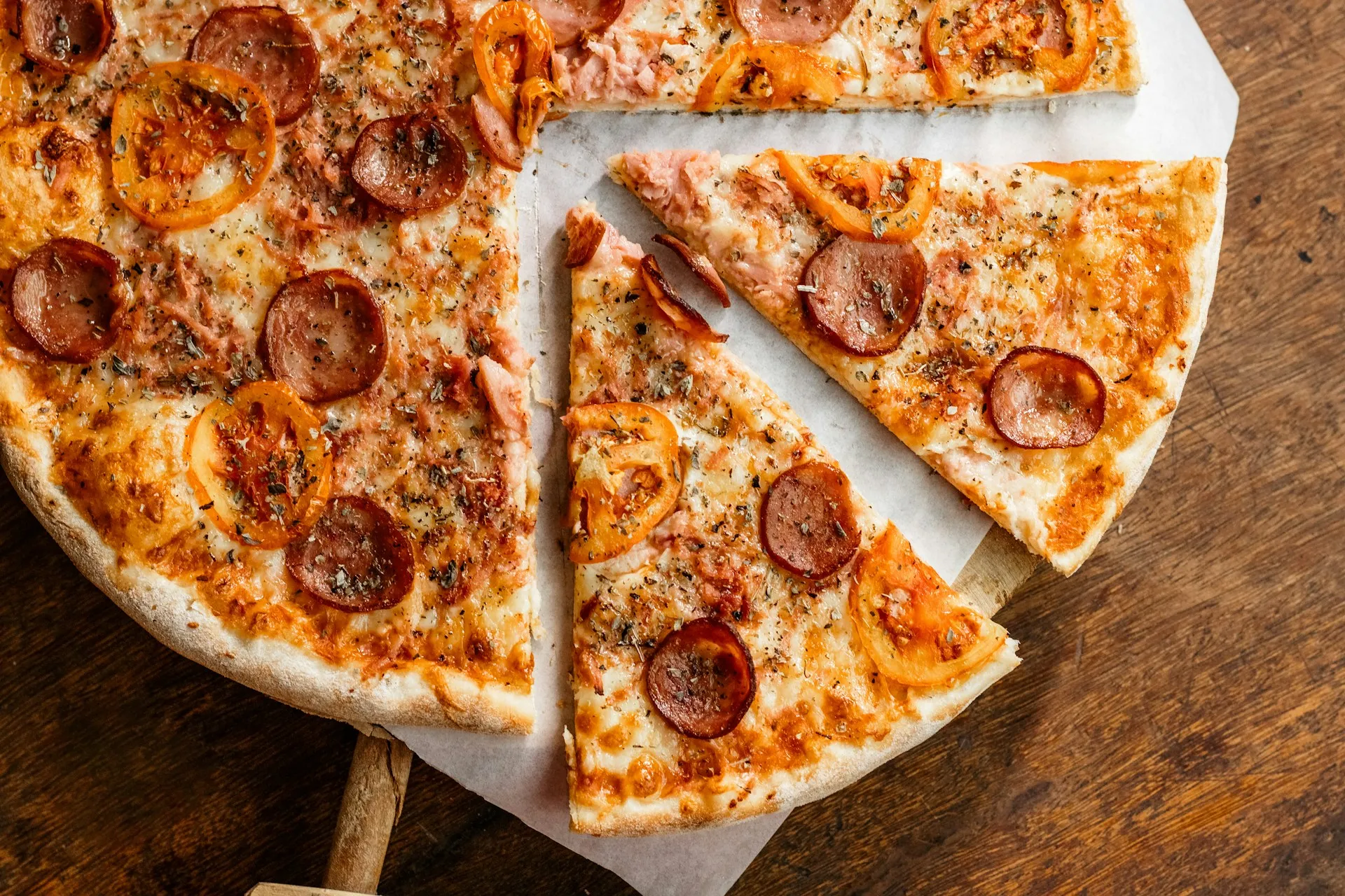 A pepperoni pizza cut into slices on a wooden table.