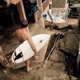 Person carrying a white surfboard walking down concrete steps outdoors.