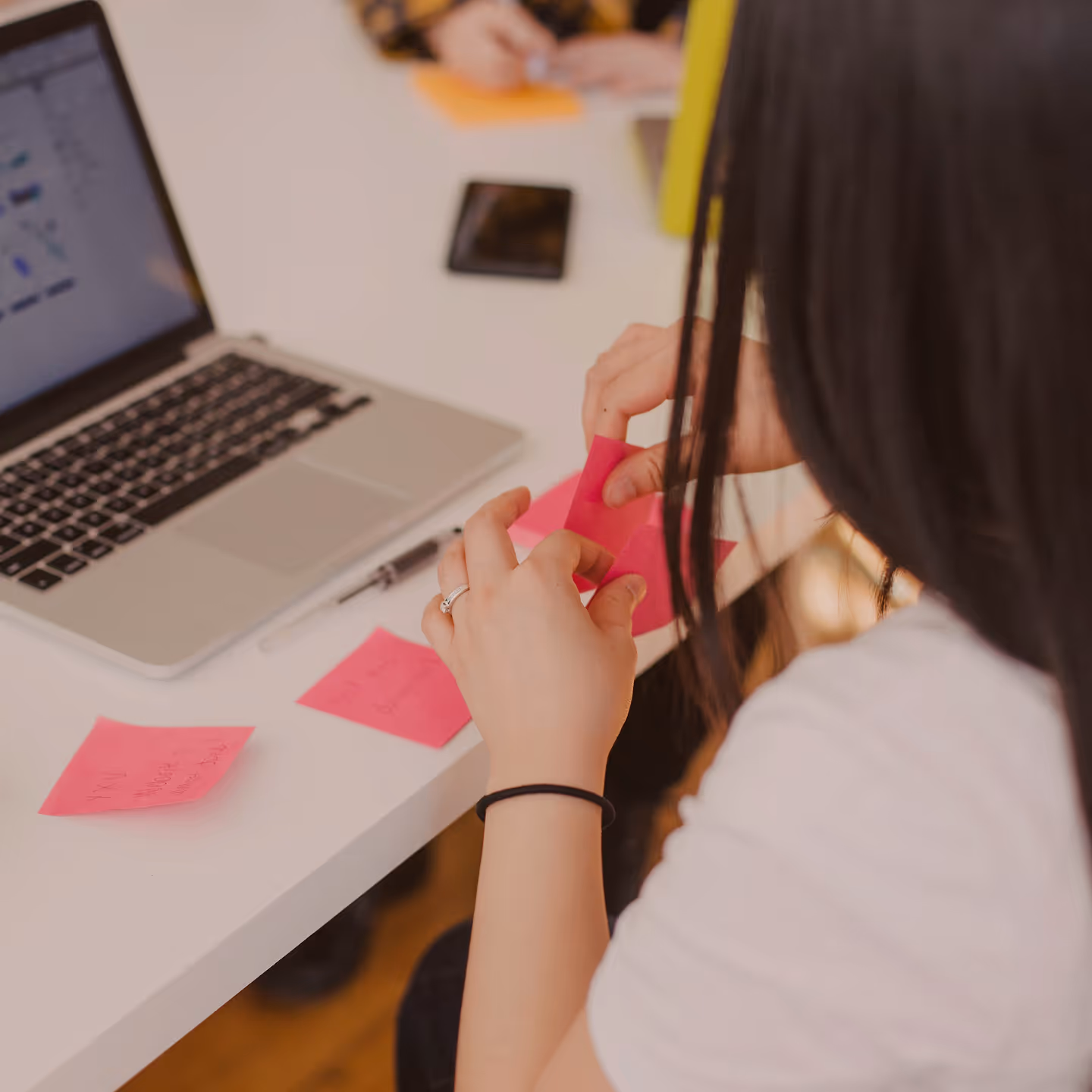 Photograph of a woman working at a laptop with sticky notes on the desk during a collaborative session.