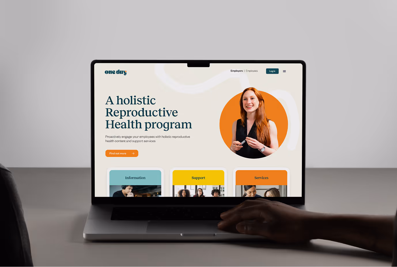 Photograph of a hand touching a laptop with One Day landing page