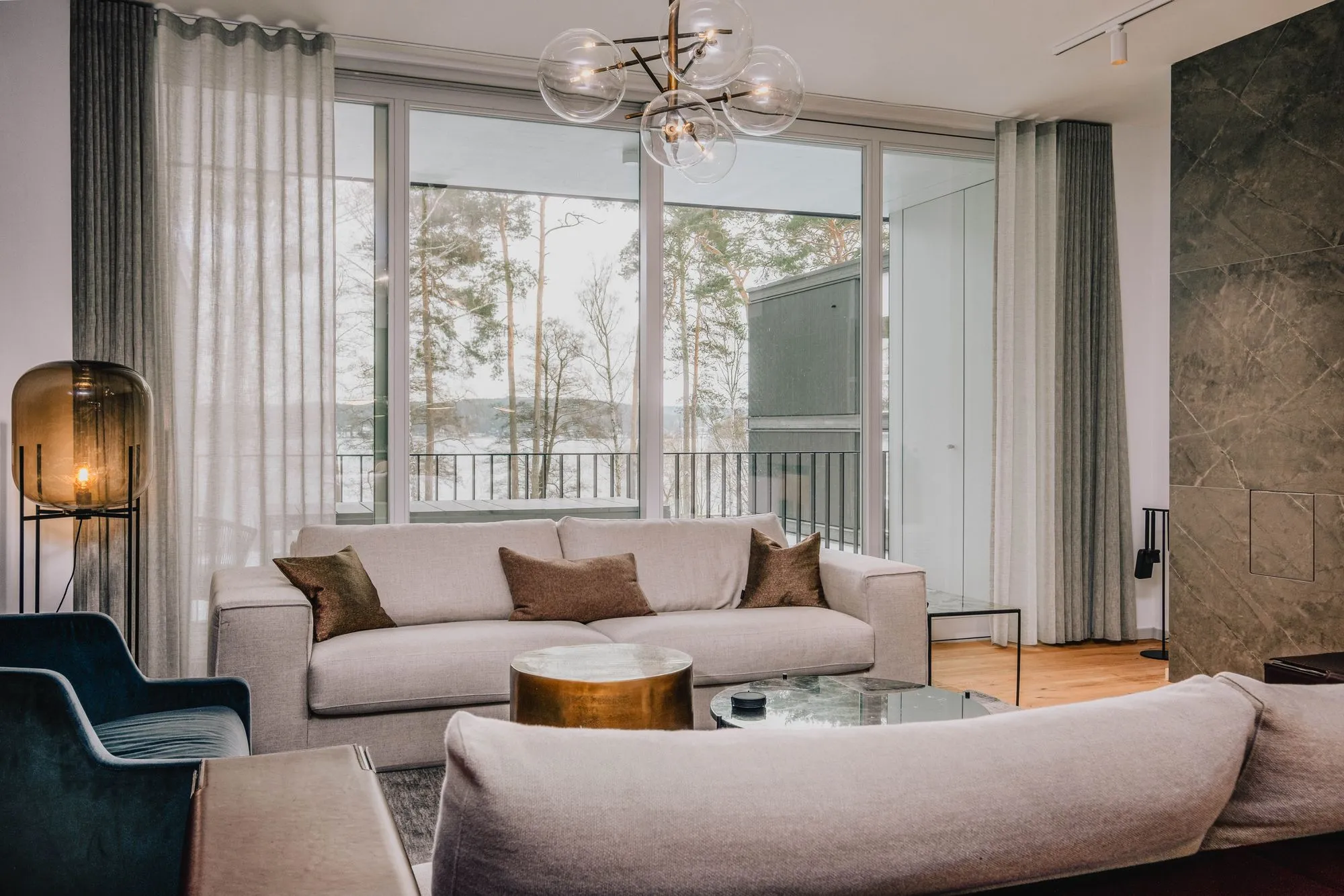 Ein modernes Wohnzimmer mit einem großen Fenster und einer bequemen Couch mit Blick auf den Scharmützelsee.