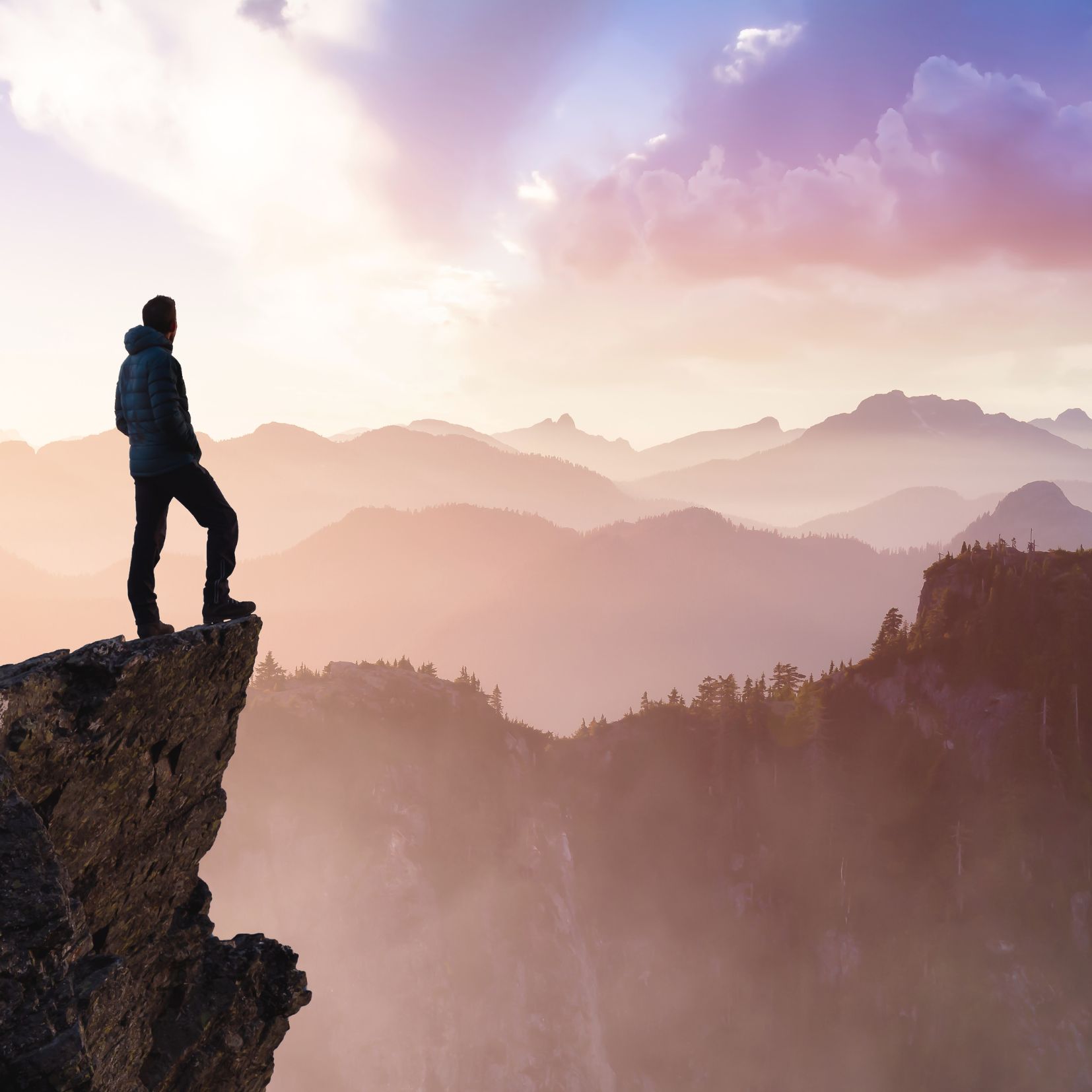 Man som står og ser utover fjellheim fra fjelltop