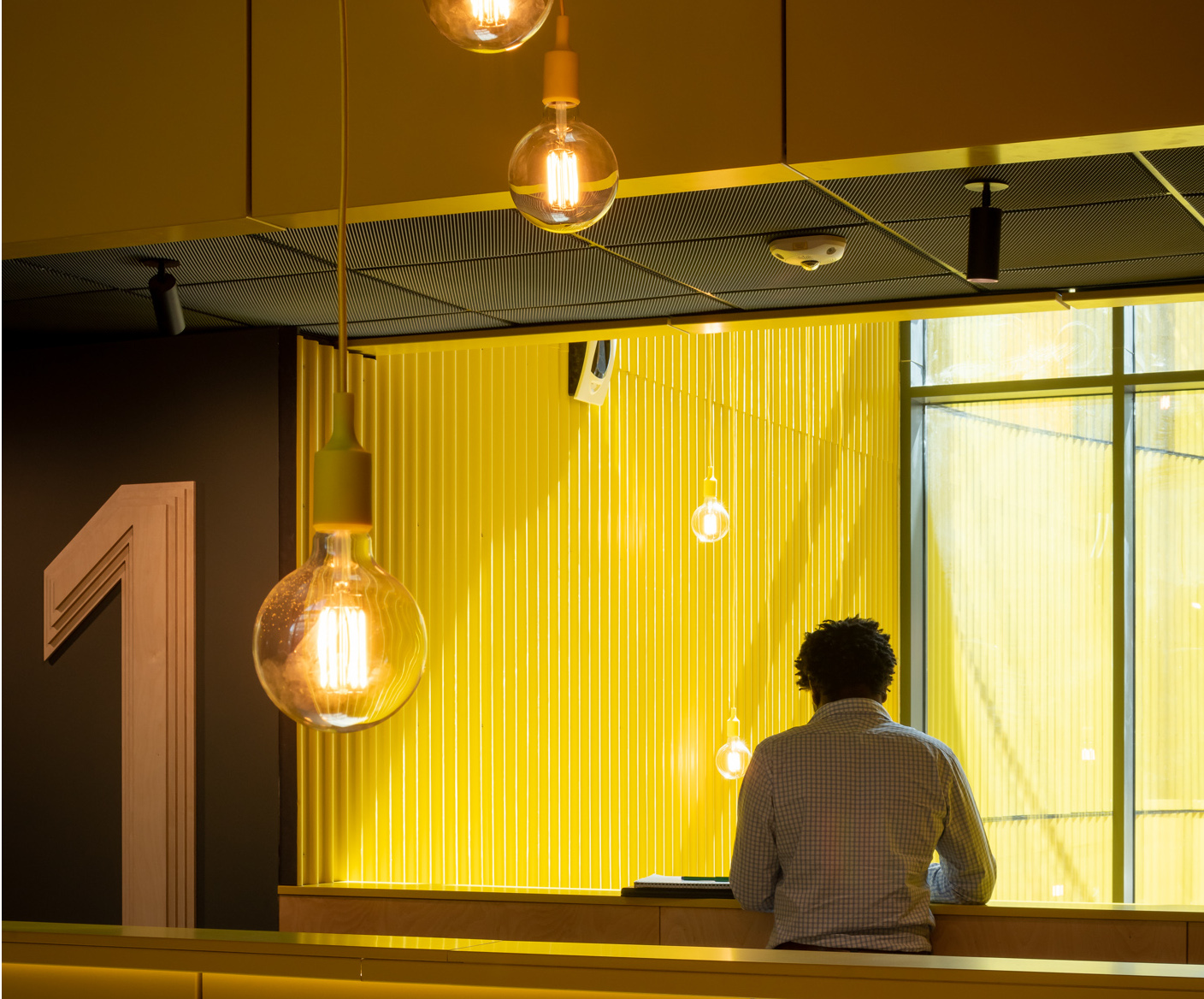 A person standing working at a laptop in an open area in the Brighton workspace