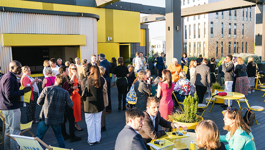a group of people at an event standing around a yellow table