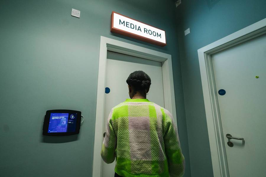 A person entering a room with the sign 'Media Room' above the door.