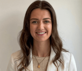 Woman smiling with brown hair in a white suit 