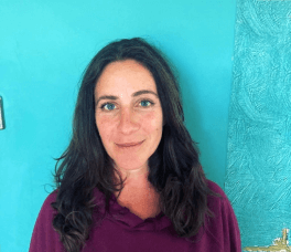Woman with black hair against a teal wall