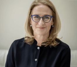 white woman wearing a black shirt and glasses. She has blonde hair and is smiling at the camera.