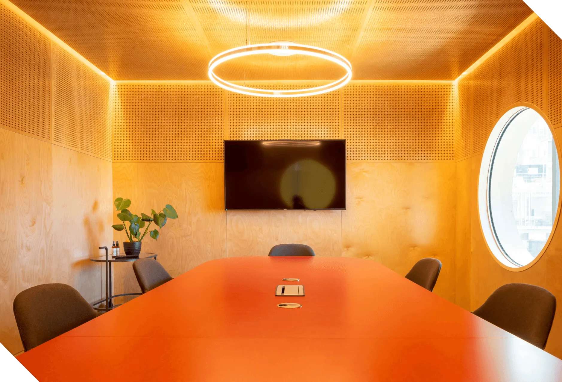 A stylish meeting room with wooden walls and round light at Plus X Innovation Brighton