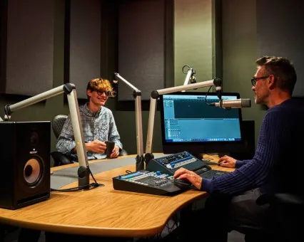 Two people talking into microphones in the podcasting suite at Plus X Innovation Brighton