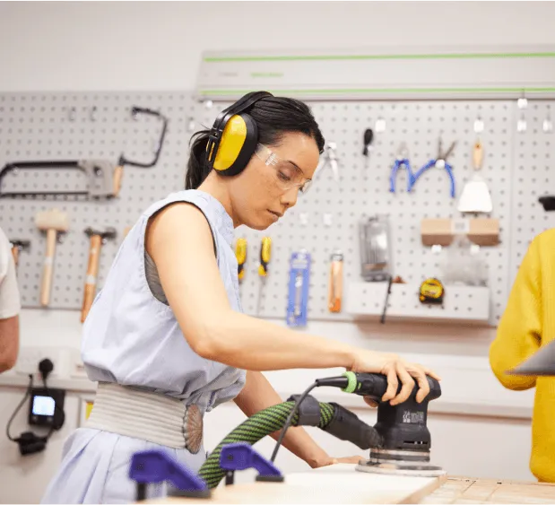 A person using a sander in the workshop at Plus X Innovation Brighton