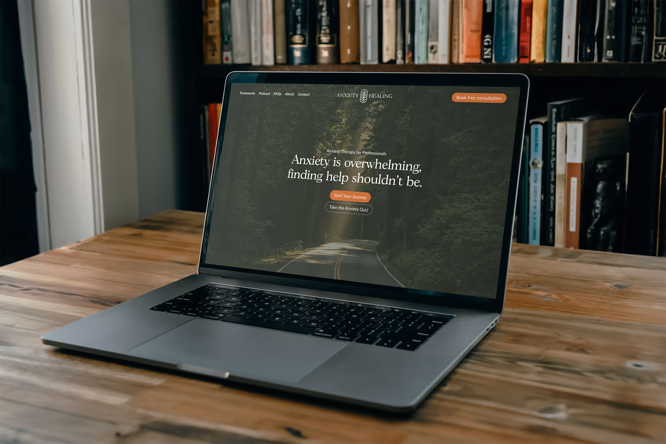 a laptop with a mockup of the anxiety healing homepage on it. Books are stacked in the background.