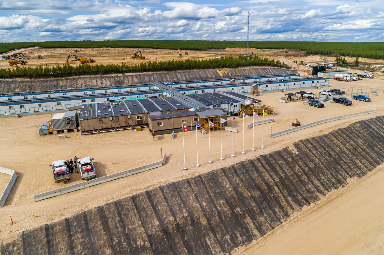 Aerial view of a large temporary camp with modular buildings, vehicles, and construction equipment nearby.