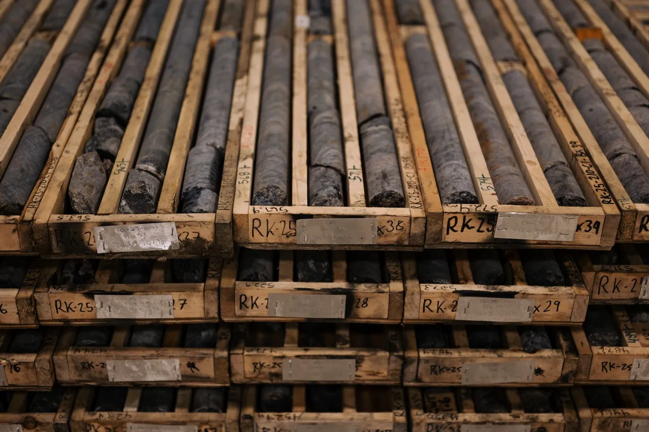 Rows of core samples organized in wooden trays with labels, stacked on shelves for geological analysis.