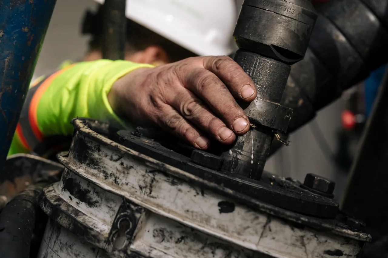 Worker's hand gripping a large industrial pipe fitting covered in dirt and grime.