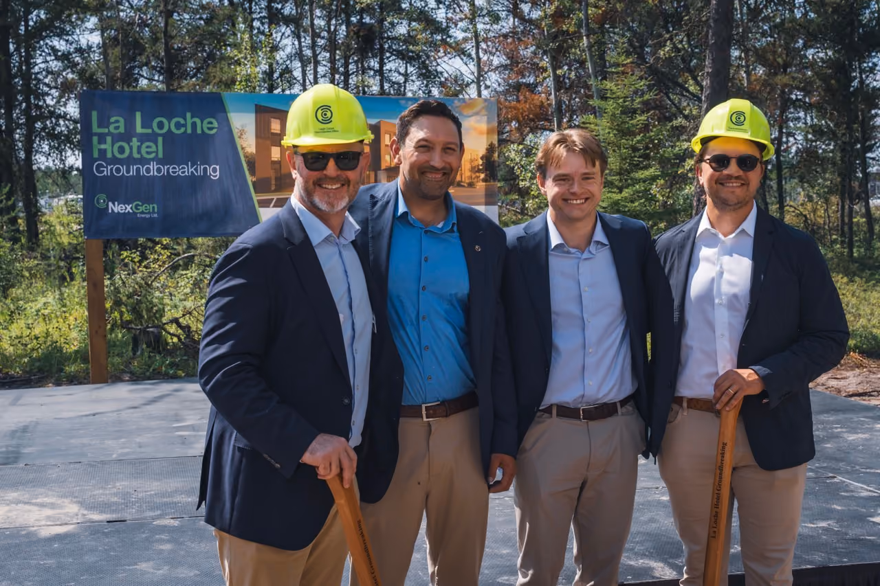 Four men in business attire stand in front of La Loche Hotel groundbreaking sign, two wear hard hats.