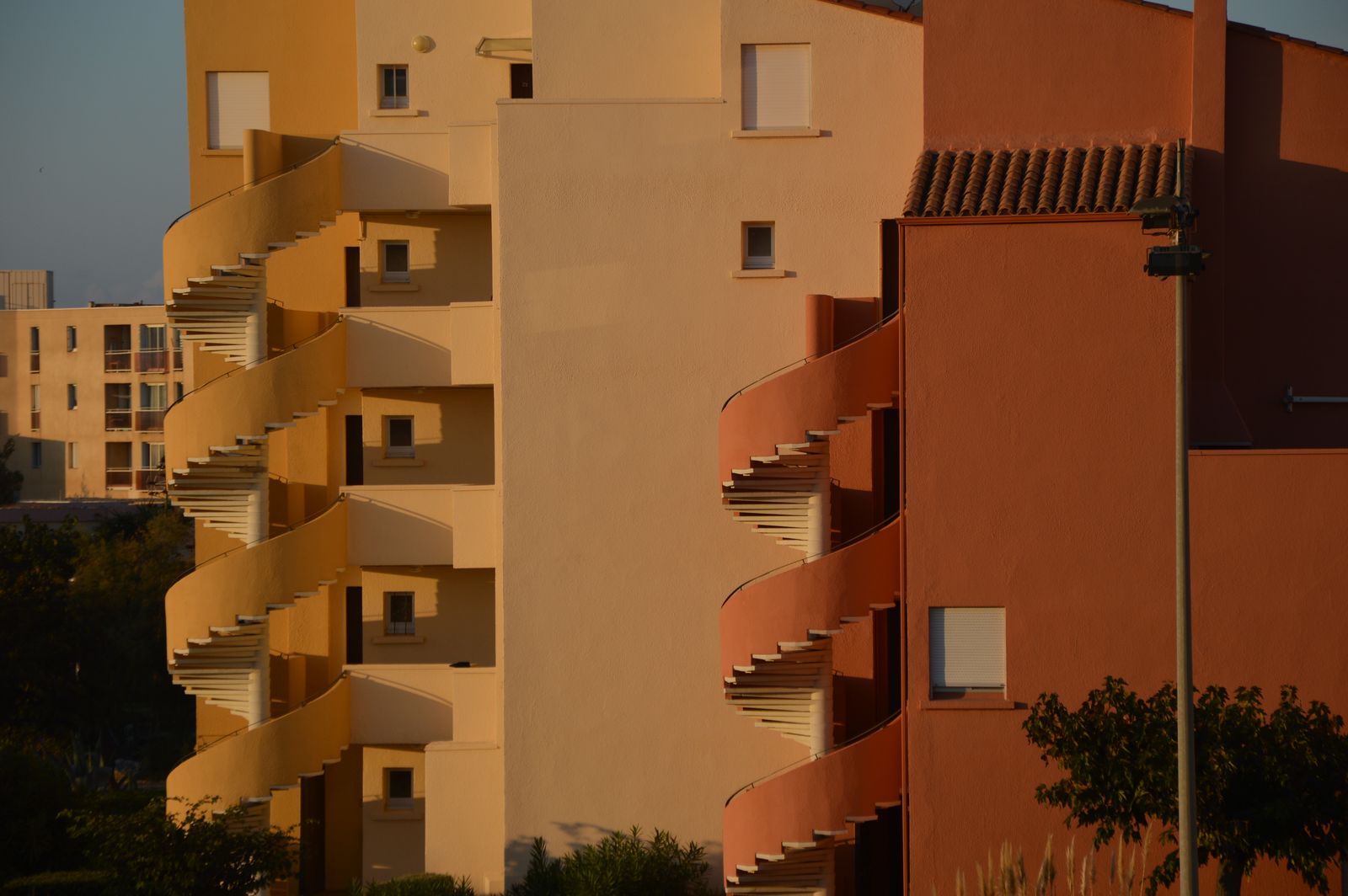 Multi story apartment complex with exterior staircases in evening light