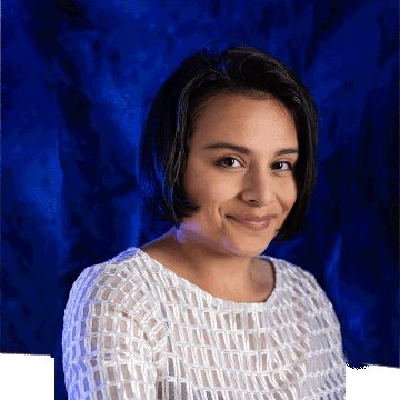 A professional latina woman with short, dark hair, wearing a white blouse in front of a dark blue backdrop.