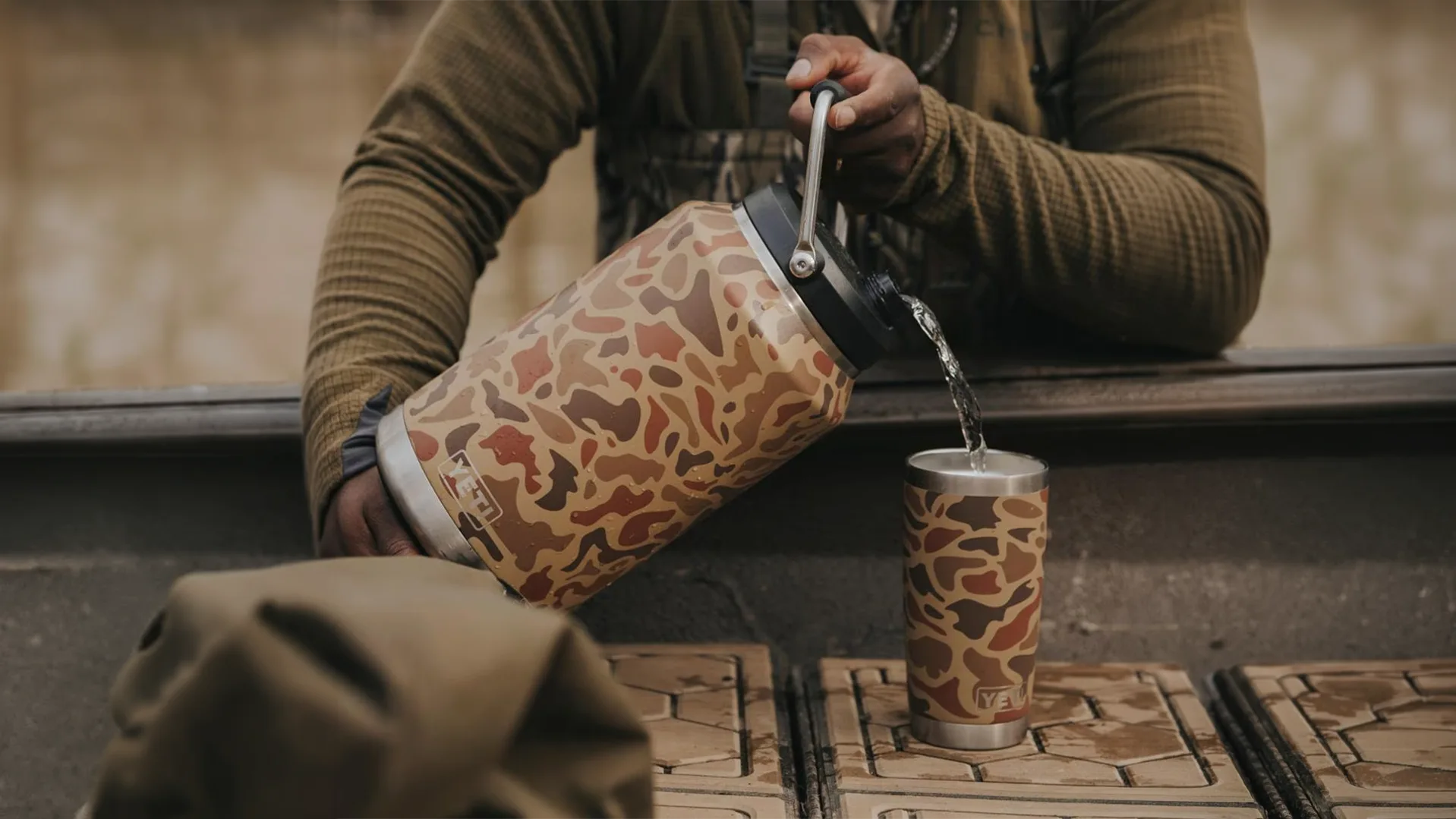 Camo YETI Rambler Jug pouring into mug highlighting rugged outdoor drinkware design and user experience improvements