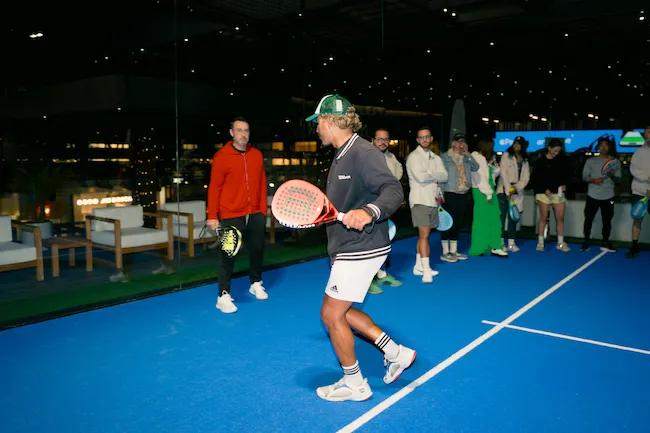Male padel teacher demonstration on court.