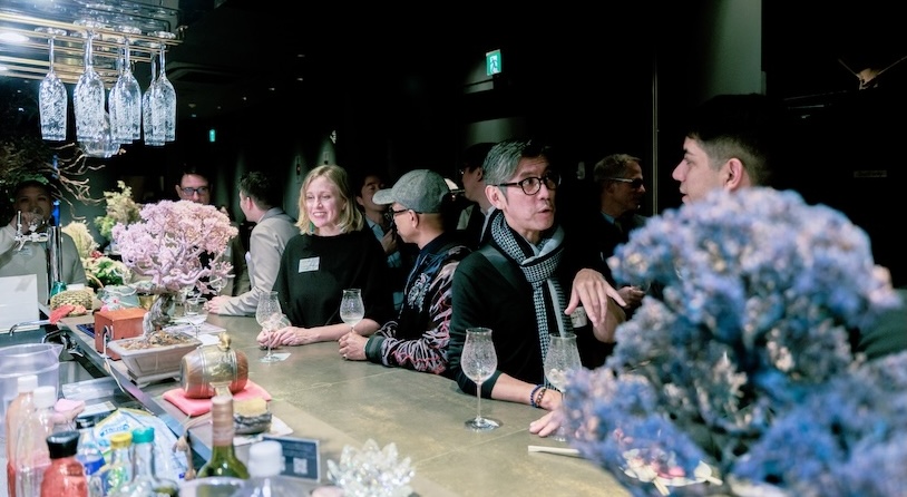 Two men engaged in a lively discussion at a table in a casual meeting setting with laptops and beverages.