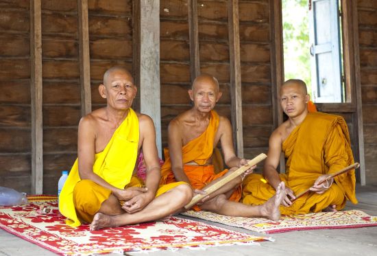 Le sud ravissant du Laos de Pakse: Champasak: Three monks sitting inside a temple in a village