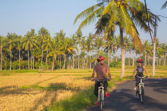 Bali aktiv erleben ab Südbali: Bali - Couple riding a bicycle through the tropical island of Bali
