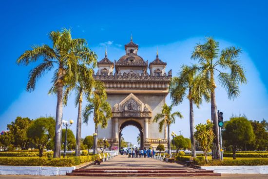 Découverte intense du Laos de Vientiane: Patuxay monument with palm trees