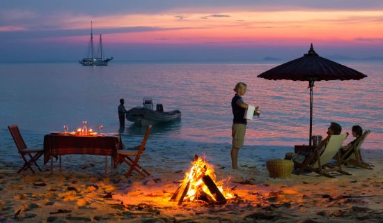 Segeltörn im paradiesischen Mergui Archipel ab Kawthaung: Raja Laut anchoring in rosy sunset by a beach with dinner table and bonfire