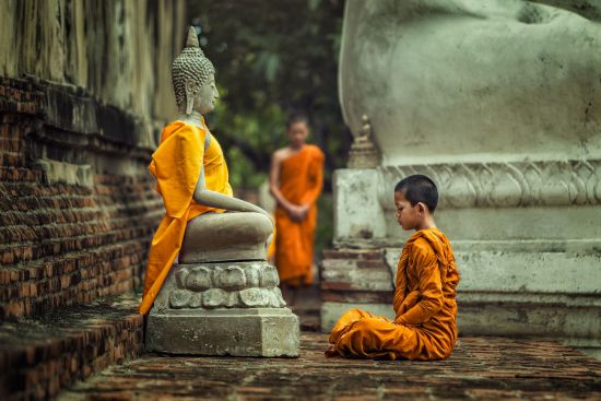 Unbekannter I-San ab Bangkok: Novice monk vipassana meditation at front of Buddha statue