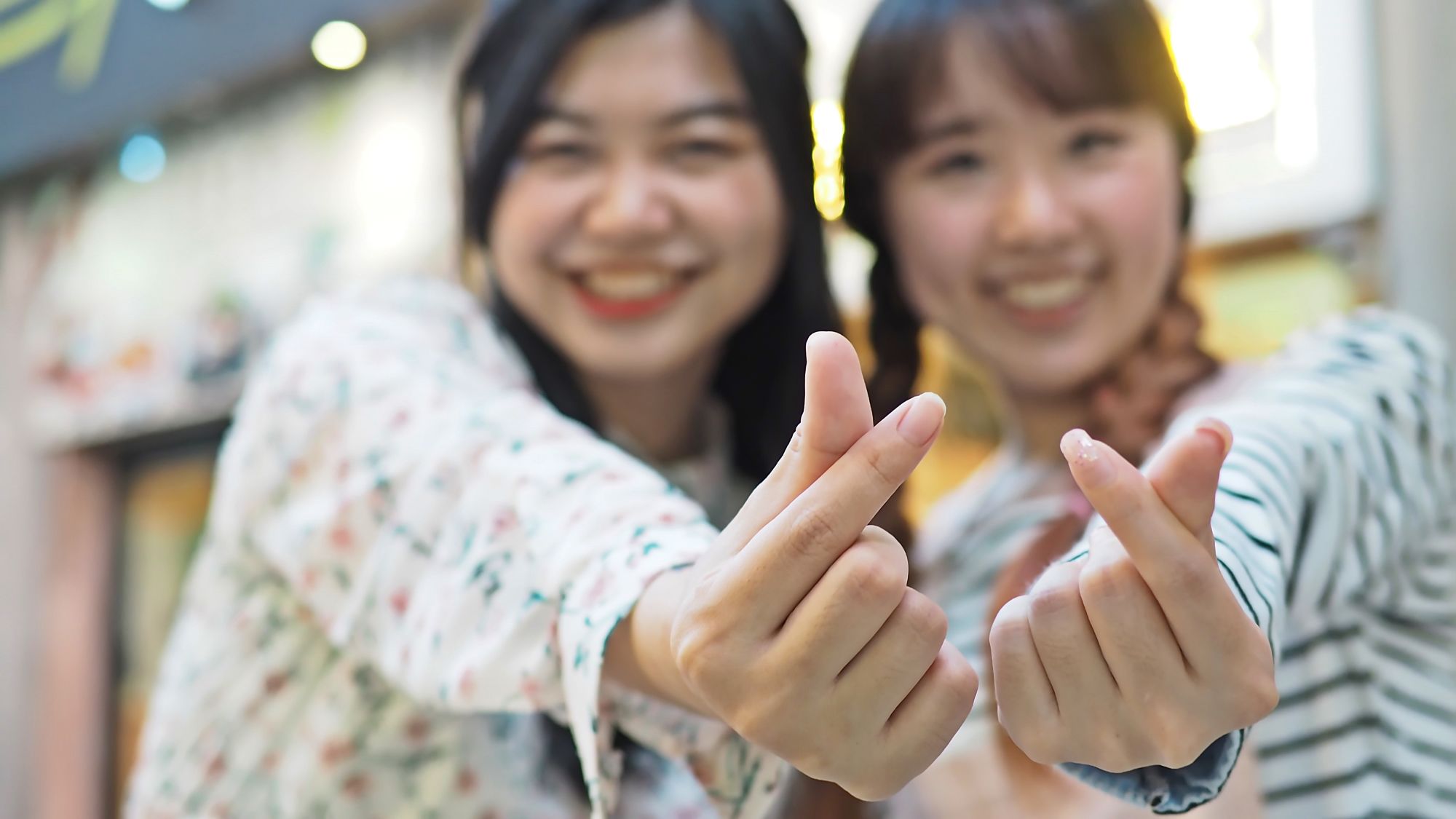 Südkorea K-Style ab Seoul: Asian girls making mini heart shaped finger hand gesture (Korean style)