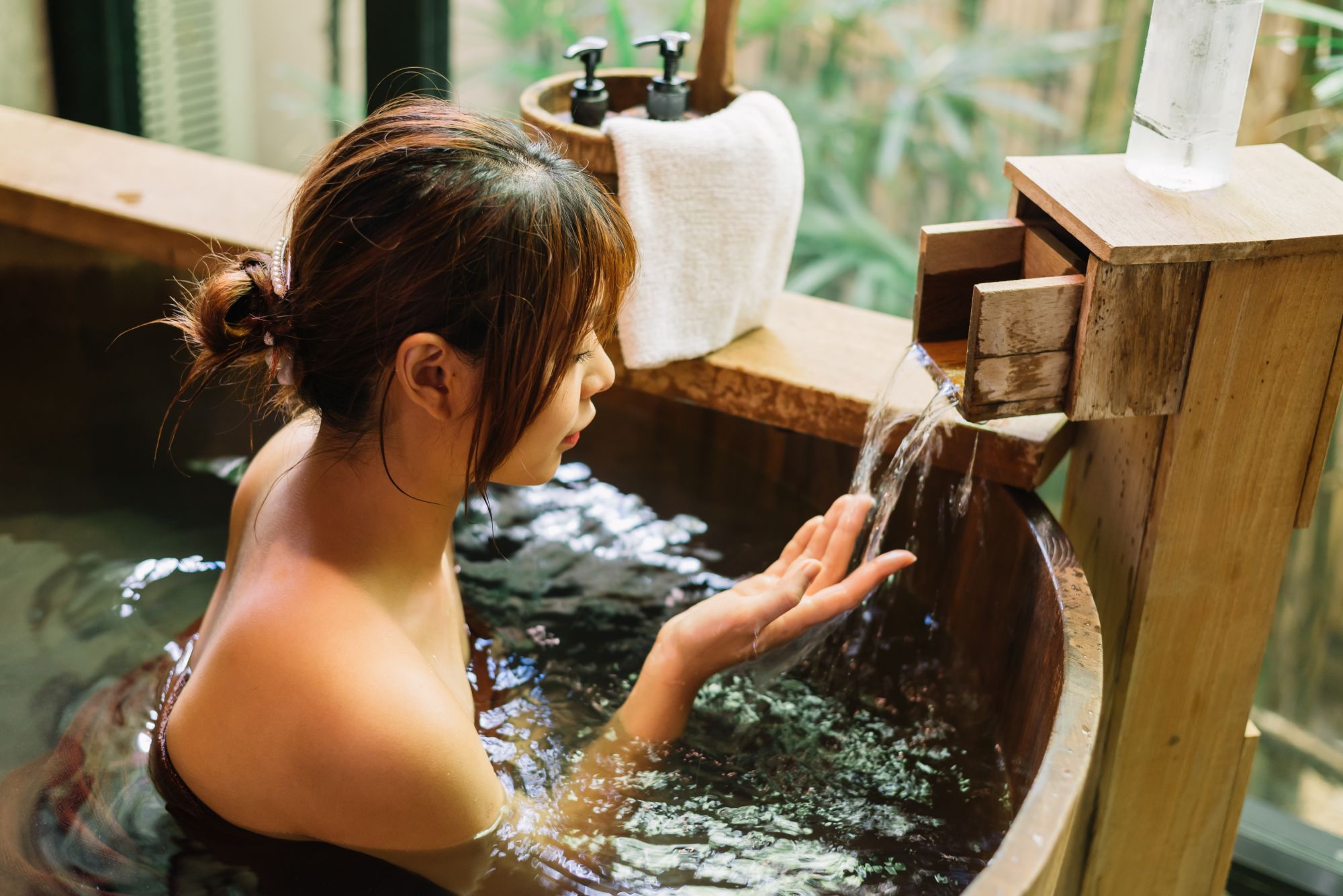Les onsen curatifs japonais de Tokyo: Woman relaxing in wooden bathtub