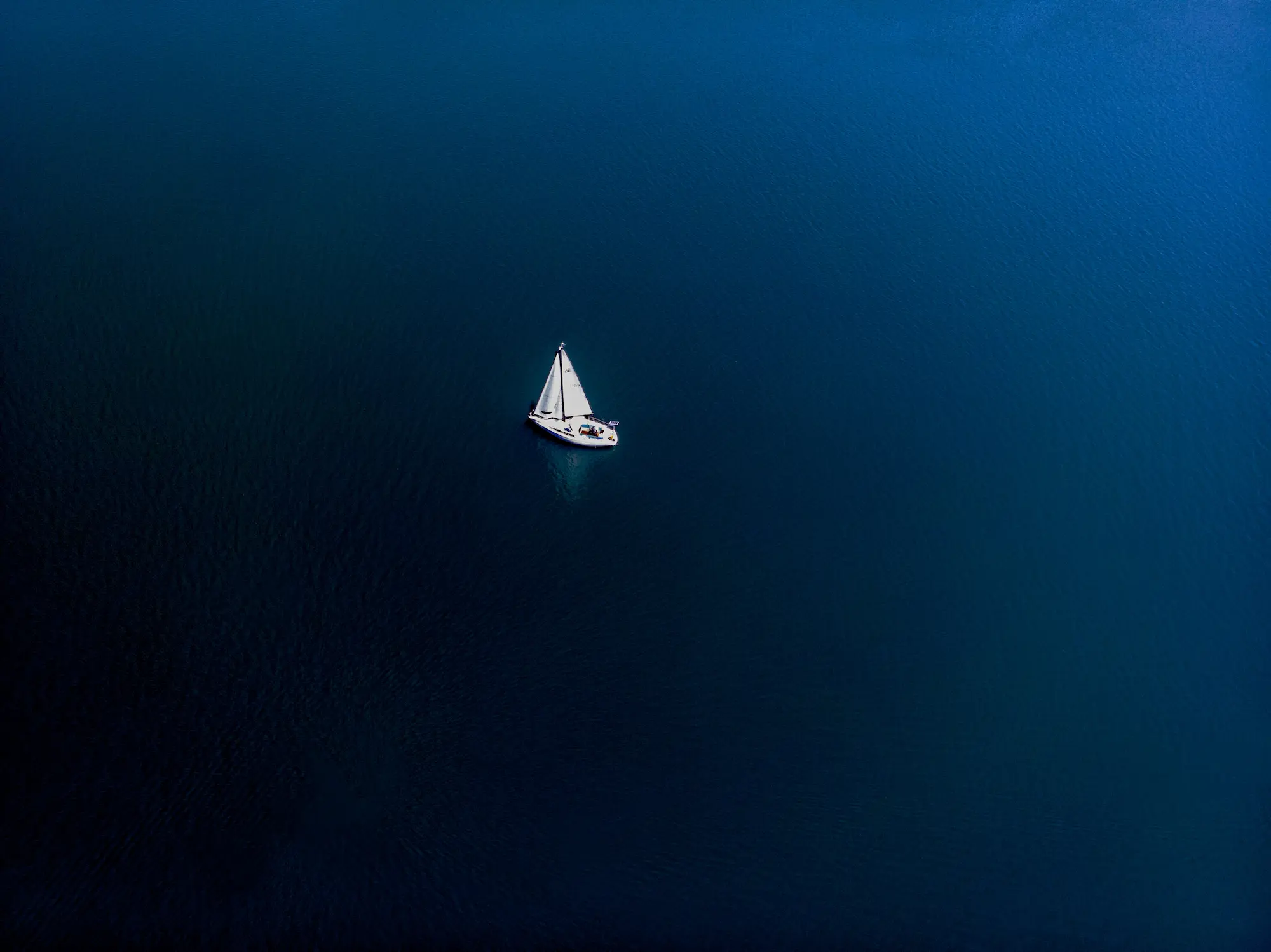 Aerial drone view of yacht sailing in crystal clear water