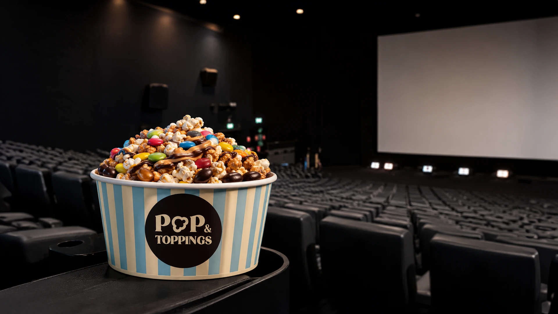 Imagen promocional de POP & TOPPINGS de Kinépolis con cubo de palomitas y toppings en una sala de cine