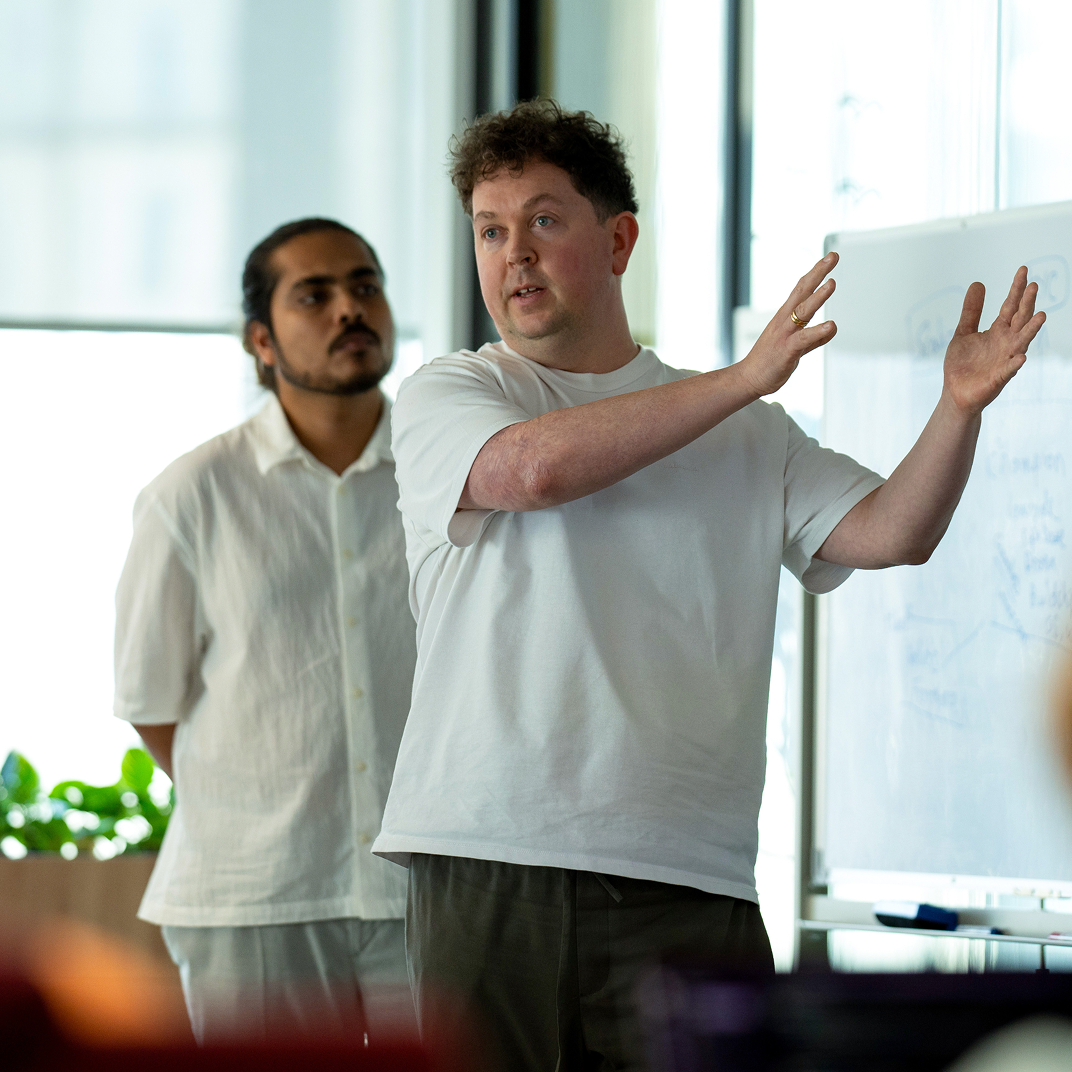 Deriv team members collaborating around a laptop at a company event, showcasing teamwork and innovation