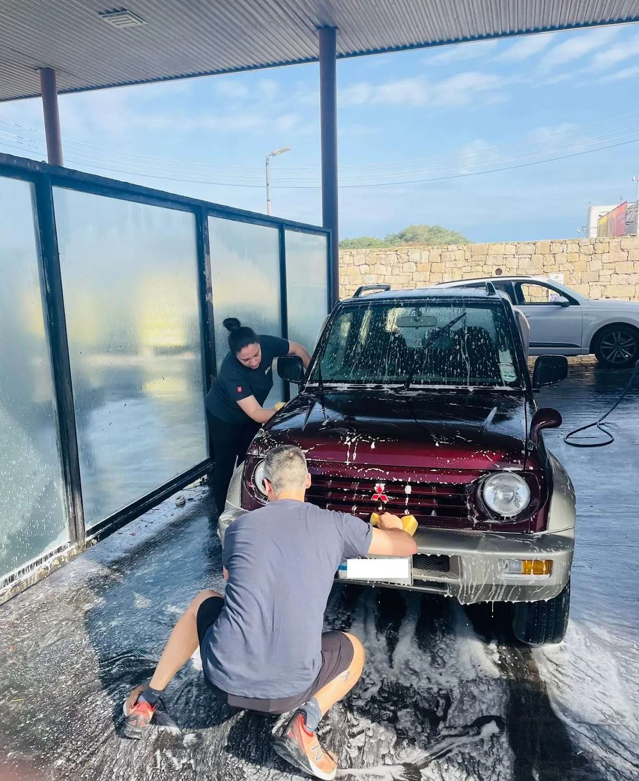 2 Deriv volunteers washing a customer’s car in the petrol station to raise funds for CSR.