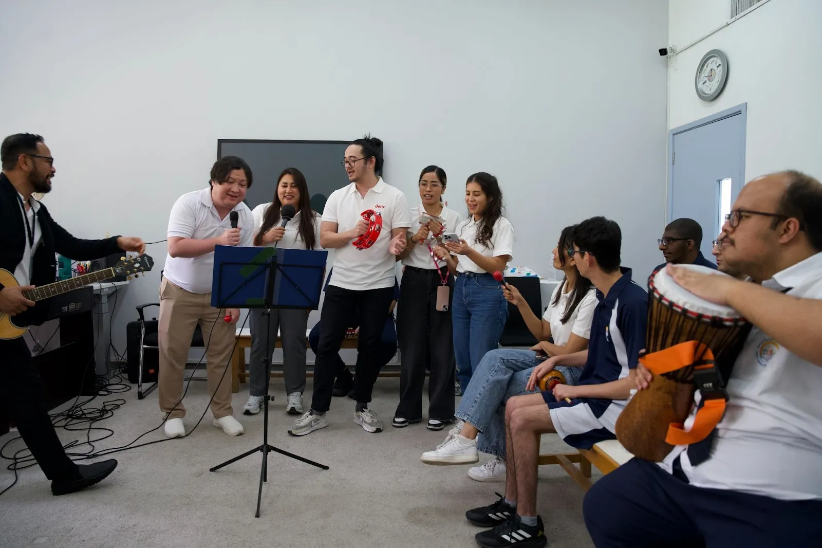  Deriv volunteers and DCSN students singing together and playing music.