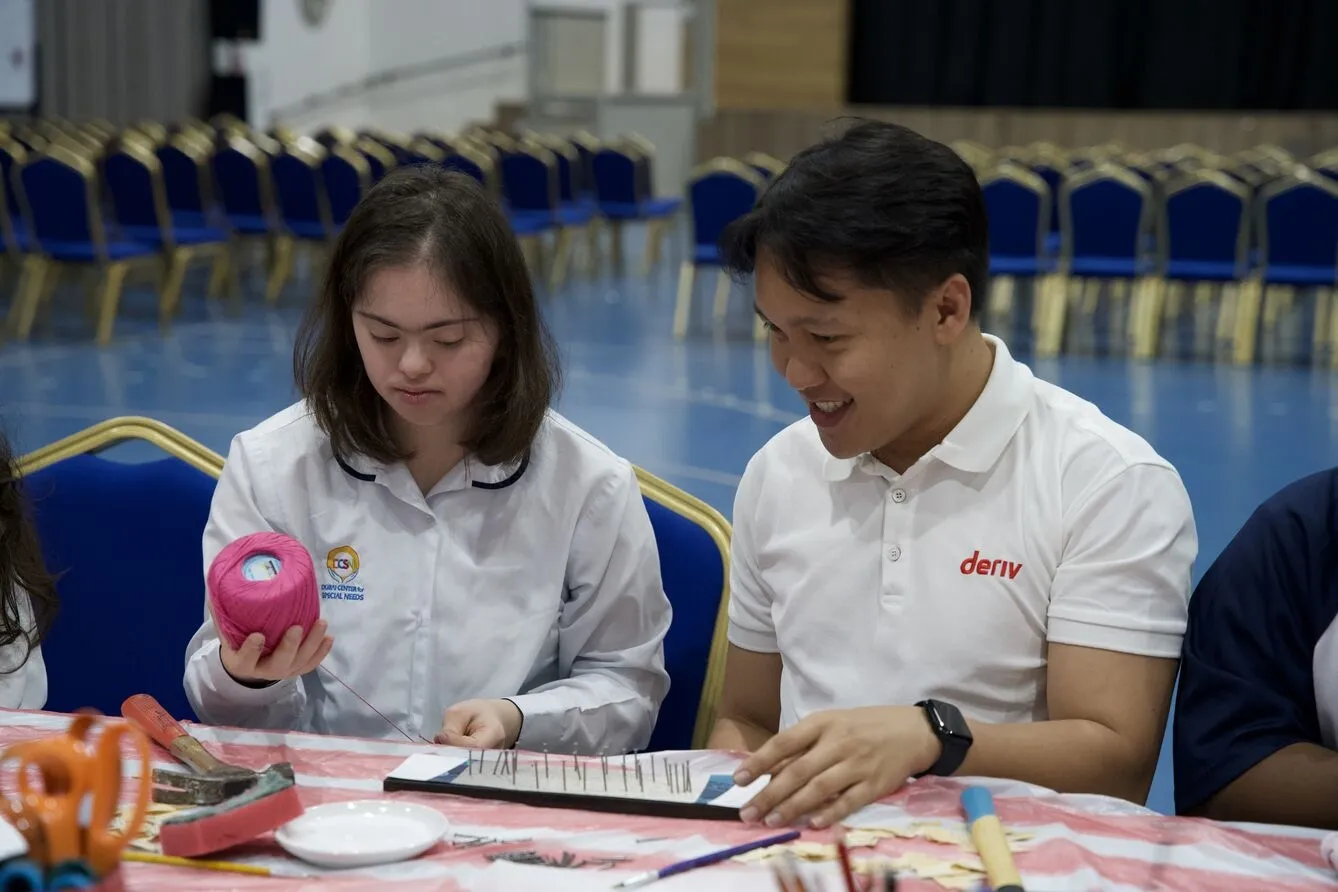 A Deriv volunteer shares a moment of creativity with a DCSN student during a craft session.