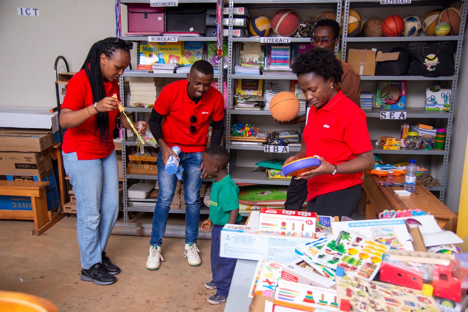 Tubiteho teacher demonstrating multi-sensory learning methods with support from Deriv volunteers in a classroom setting.‍