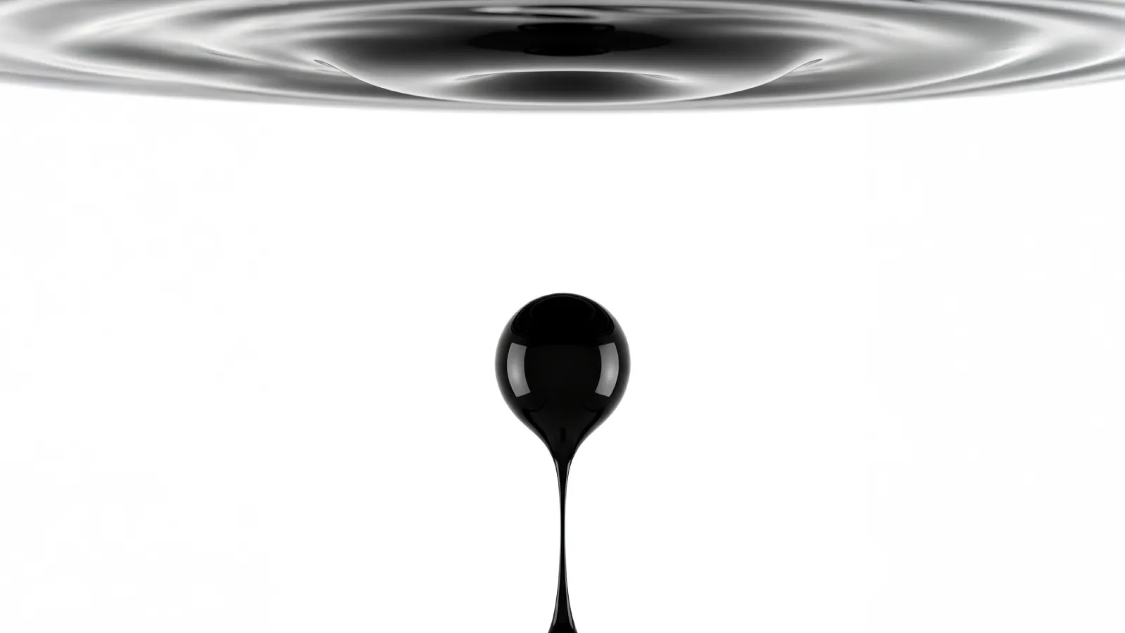 A single droplet of black crude oil suspended mid-air beneath a rippling pool of oil, against a stark white background.