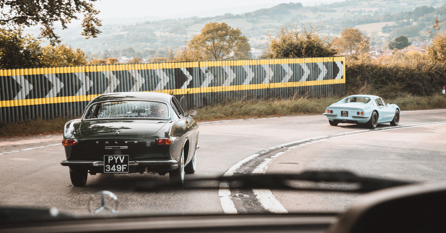 Classic cars taking a bend on a picturesque road